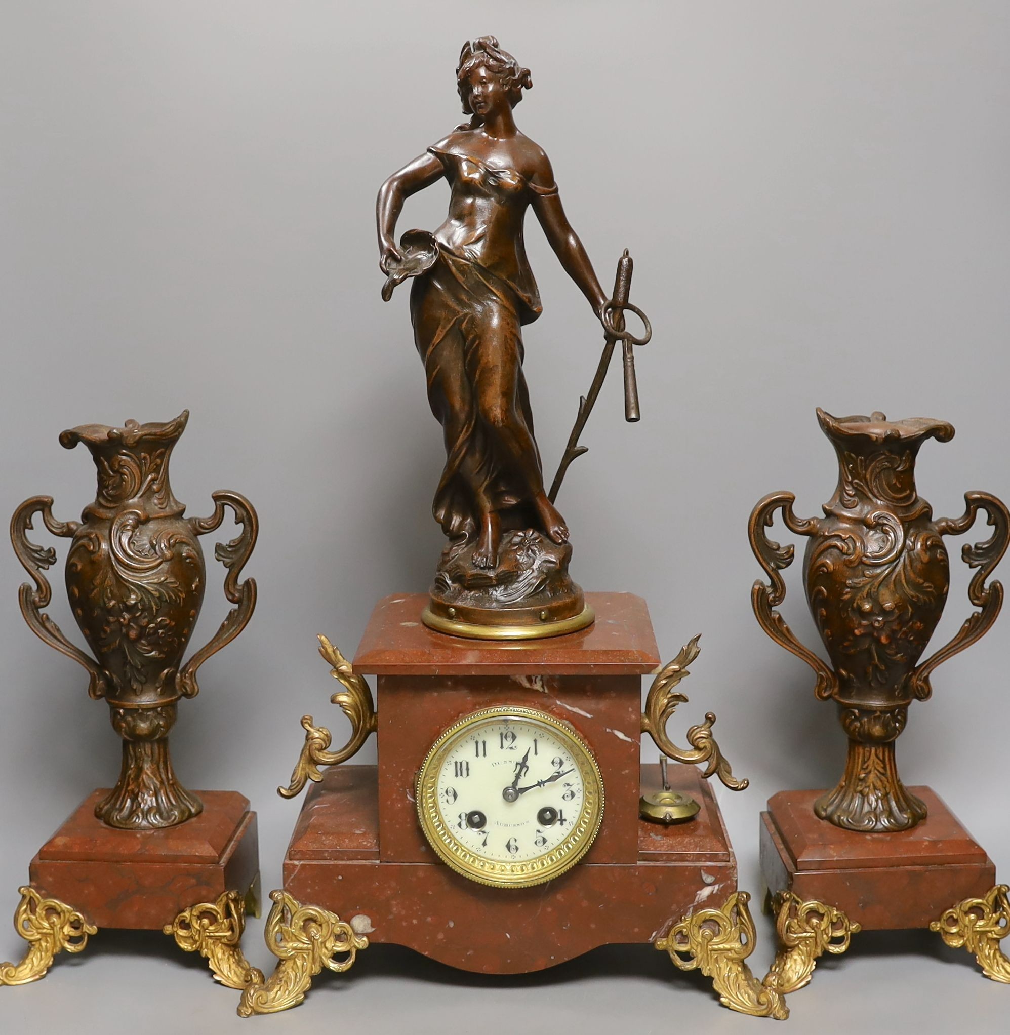 A French figurative early 20th century rouge marble clock garniture, Clock 51 cms high.